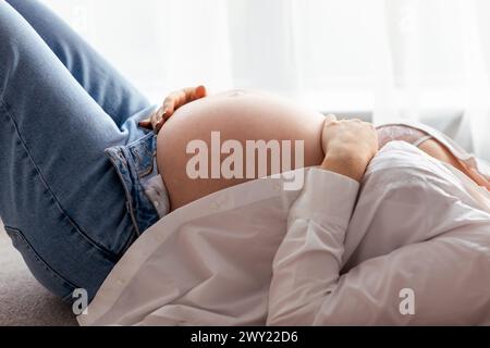 Nahaufnahme des Bauches einer schwangeren Frau, die ein auf dem Bett liegendes Baby erwartet Stockfoto