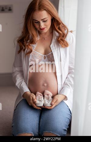 Schöne rothaarige schwangere Frau mittleren Alters, die zu Hause ein Baby erwartet Stockfoto