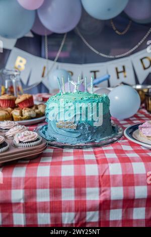 Eine blau-blaue Meerjungfrauen-Geburtstagskuche mit Kerzen, Ballons, süßen Leckereien, essbarer Glasur, Muffins, Cupcakes und mehr! Stockfoto