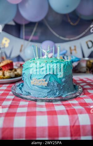 Eine blau-blaue Meerjungfrauen-Geburtstagskuche mit Kerzen, Ballons, süßen Leckereien, essbarer Glasur, Muffins, Cupcakes und mehr! Stockfoto