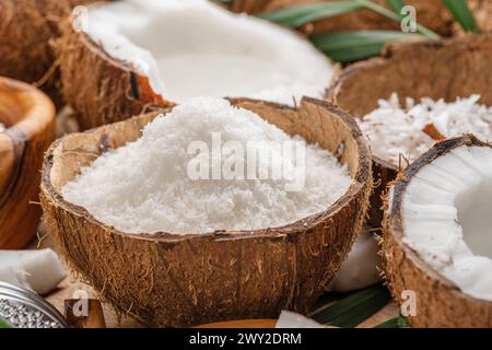 Frisch geöffnete Kokosnüsse zusammen mit Kokosscheiben, Flocken und Kokosblättern auf einem Holztisch. Schöner Hintergrund für Ihre Projekte. Stockfoto