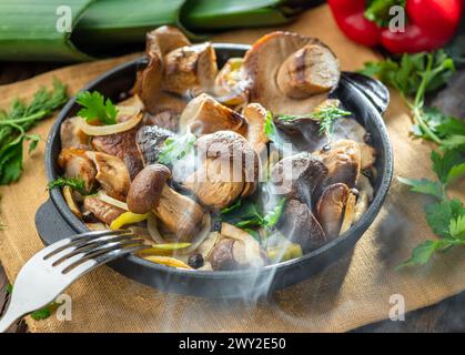 Garen Sie einfach dampfende Steinpilze in der Pfanne auf dem Holztisch. Draufsicht. Stockfoto