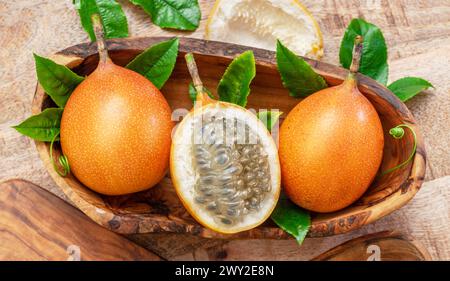 Granadilla-Früchte mit Blättern auf Holztisch. Draufsicht. Stockfoto