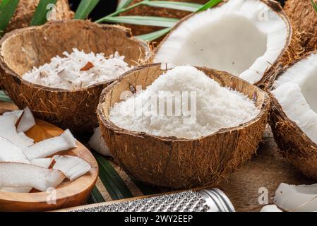 Frisch geöffnete Kokosnüsse zusammen mit Kokosscheiben, Flocken und Kokosblättern auf einem Holztisch. Schöner Hintergrund für Ihre Projekte. Stockfoto
