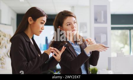 Entwickler messen 3D-Gebäudemodelle, um Blaupausen zu erstellen, und untersuchen die Maquette, um industrielle Skizzen zu entwerfen. Das Architektenteam arbeitet an industriellen Entwürfen im Coworking Space. Stockfoto