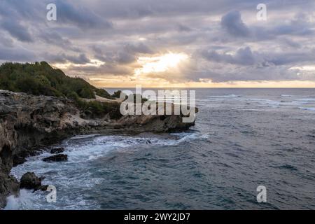 Die Sonne geht langsam über zerklüftete Klippen auf und trifft auf das raue türkisfarbene Wasser des Pazifischen Ozeans entlang des Mahaulepu Heritage Trail in Koloa, Hawaii Stockfoto