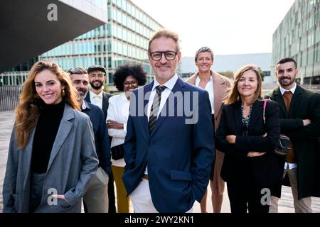 Fröhlich lächelndes Team aus verschiedenen Geschäftsleuten in formellem Anzug, das selbstbewusst in die Kamera blickt Stockfoto