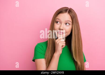 Foto-Porträt des hübschen Teenagermädchens Berührung Kinn gesinnter leerer Raum gekleidet stilvolles grünes Outfit isoliert auf rosa Farbe Hintergrund Stockfoto