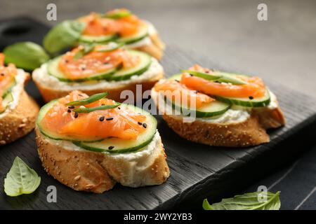 Leckere Kanapees mit Lachs, Gurke und Frischkäse auf dem Tisch, Nahaufnahme Stockfoto