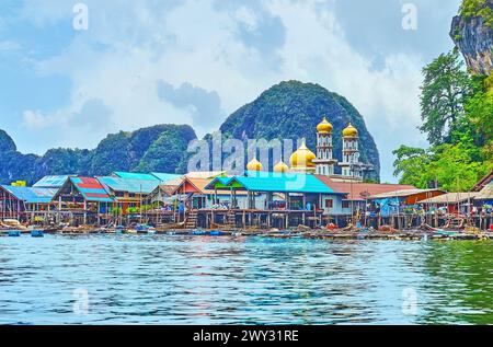 Die alten Holzpfahlhäuser und die goldene Kuppel des Dorfes Ko Panyi am Fuße des Felsens, Phang Nga Bay, Thailand Stockfoto