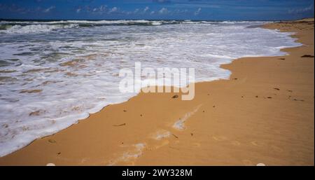 Dramatische Hintergrundfarben, während die weißen Wellen oder die weißen schäumenden Wellen an einem Sandstrand an der Sunshine Coast in Kawana Queensland eintauchen Stockfoto