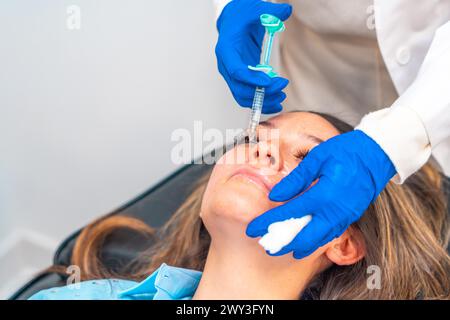 Der Arzt cosmetologist macht den verjüngenden Gesichtseinspritzungen Verfahren zur Straffung und Glättung der Falten auf der Haut einer schönen Stockfoto