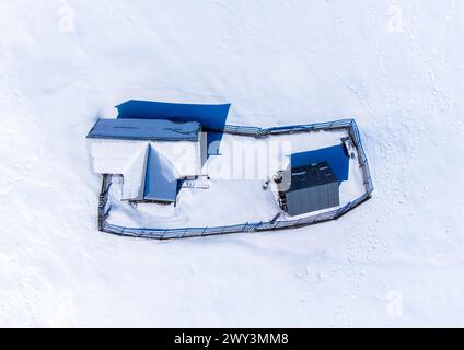 Ein Blick aus der Vogelperspektive auf ein einsames altes Haus auf einem schneebedeckten Feld Stockfoto