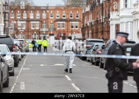 Polizei am Tatort einer tödlichen Schießerei in der Comeragh Road, West Kensington, London, Großbritannien. Offizier in forensischen Overalls auf dem Weg zum Tatort Stockfoto