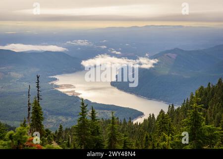 Ein Blick über dunkle Tannen zur silbrigen Oberfläche des Lake Cushman unter einer tiefen Wolkenbank vom Mount Ellinor aus, Olympic National Forest, Washington. Stockfoto