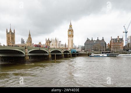 Rote Londoner Busse überqueren die Westminster Bridge. Dahinter steht Big Ben und die Houses of Parliament, ein ikonisches Symbol der britischen Demokratie und des britischen Erbes. Stockfoto