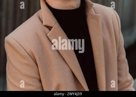 Details aus beigefarbenem Männermantel und schwarzem Rollkragen. Klassische Street-Oberbekleidung Stockfoto