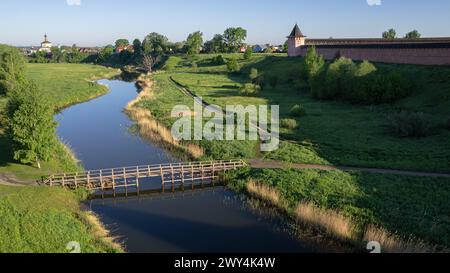 Blick aus der Vogelperspektive auf eine Holzbrücke über einen kleinen Fluss, Spätfrühling in Suzdal. Stockfoto