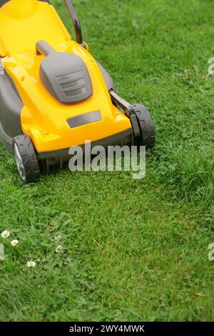 Gelber Rasenmäher auf dem grünen Gras im Hof Stockfoto