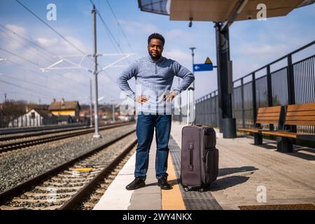 Ein wütender Mann mit einem Koffer, der auf einem Bahnhof steht. Stockfoto