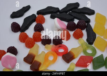 Süßigkeiten in Form eines schwarzen Autos, Himbeeren, Brombeeren, Cola-Flaschen, farbige Schlüssel, Diamanten mit dem Alphabet. Stockfoto