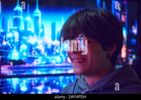 Junger Mann, der in einer Brille steht, mit einer urbanen Szene, die sich in einer Brille spiegelt. Nachtstadt mit Lichtern, Wolkenkratzern und lebhaften Straßen Stockfoto