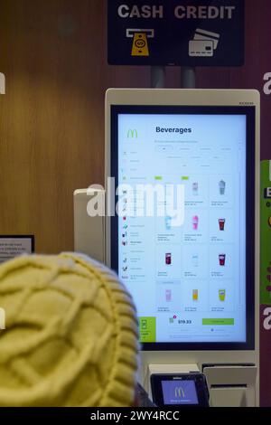 Nueva York, USA - 27. März 2024: Rückansicht eines Kunden bei McDonald's, der Getränke auf einem Touchscreen auswählt, mit Zahlungsoptionen und Preisen. Stockfoto