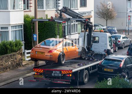 Beschädigtes Auto wird von einem Pannenwagen in einer engen Straße in Essex, Großbritannien, geborgen Stockfoto