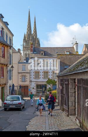 Quimper, Frankreich - 24. Juli 2017: Touristen streifen auf einer Straße mit Blick auf die Kathedrale Saint Corentin von Quimper. Stockfoto