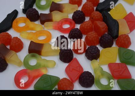 Süßigkeiten in Form eines schwarzen Autos, Himbeeren, Brombeeren, Cola-Flaschen, farbige Schlüssel, Diamanten mit dem Alphabet. Stockfoto