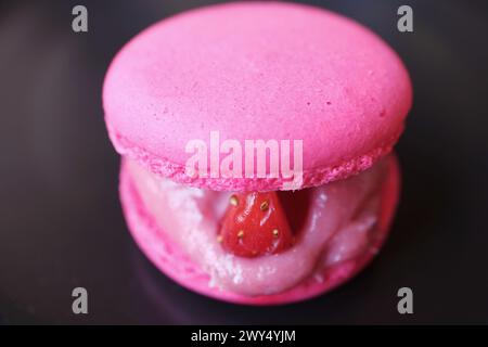 Köstlicher rosafarbener Macaron gefüllt mit frischer Erdbeere und Creme Stockfoto