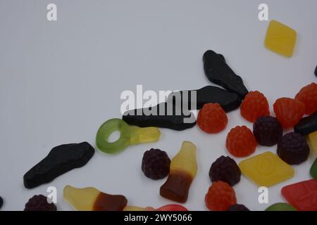 Süßigkeiten in Form eines schwarzen Autos, Himbeeren, Brombeeren, Cola-Flaschen, farbige Schlüssel, Diamanten mit dem Alphabet. Stockfoto