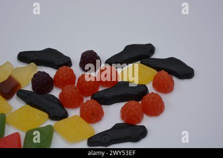 Süßigkeiten in Form eines schwarzen Autos, Himbeeren, Brombeeren, Cola-Flaschen, farbige Schlüssel, Diamanten mit dem Alphabet. Stockfoto