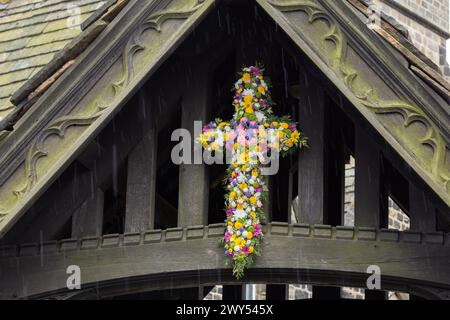 Ein florales Osterkreuz über dem Lychgate in der St. John's Church of England in Baildon, Yorkshire, England. Dies ist bekannt als „blühendes Kreuz“. Stockfoto