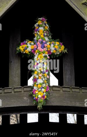 Ein florales Osterkreuz über dem Lychgate in der St. John's Church of England in Baildon, Yorkshire, England. Dies ist bekannt als „blühendes Kreuz“. Stockfoto