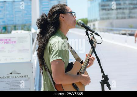 Profilansicht eines jungen Buskers mit langen lockigen Haaren mit Sonnenbrille, in Argentinien Gitarre spielen und singen, mittags arbeiten, Kopierraum. Stockfoto
