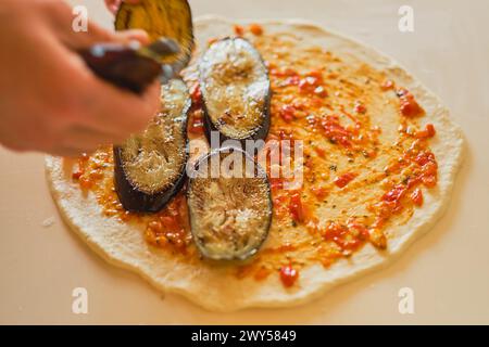 Der Koch setzt Auberginen und Mozzarella auf Calzone, köstliches traditionelles italienisches Gericht, gastronomischer Ausflug nach Italien, verschwommener Hintergrund Stockfoto