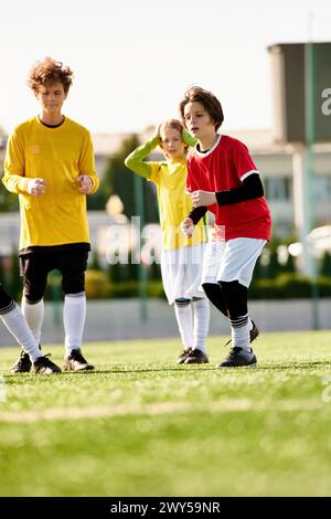 Eine dynamische Gruppe junger Menschen steht triumphierend auf einem Fußballfeld und strahlt Energie und Teamarbeit aus, wenn sie ihren Sieg feiern. Stockfoto