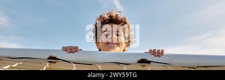 Ein junger Mann steht selbstbewusst hinter einem Fußballtor und ist bereit, sich gegen eintreffende Schüsse während eines Spiels zu verteidigen. Stockfoto