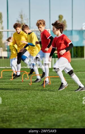 Eine Gruppe kleiner Jungen spielt begeistert ein Fußballspiel auf einem grasbewachsenen Feld, läuft, tritt und zieht den Ball mit Spannung und Konzentration weiter. Stockfoto