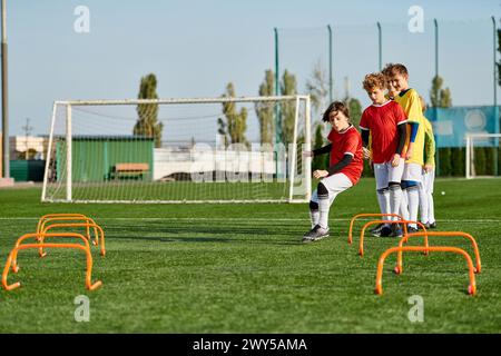 Eine Gruppe energiegeladener kleiner Kinder, die sich auf einem sonnigen Feld bei einem freundlichen Fußballspiel engagieren. Sie dribbeln, passieren und schießen den Ball und zeigen Teamwork Stockfoto