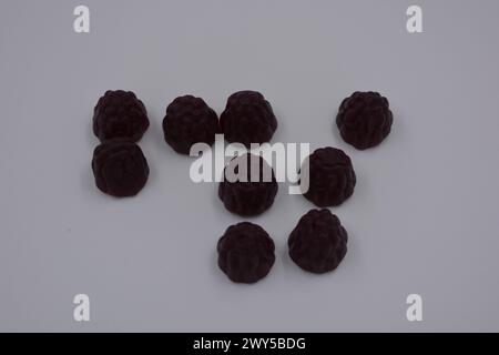 Ungewöhnliche Süßigkeiten, farbige Gelee-Bonbons in Form von Früchten. Schwarze Gelee brombeere und Himbeere sind auf weißem Hintergrund angeordnet. Stockfoto