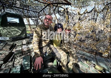 UKRAINE - 31. MÄRZ 2024 - drei Soldaten sitzen auf einem Panzer der 1. Panzerbrigade der ukrainischen Bodenstreitkräfte. Stockfoto