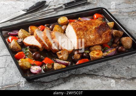 Gesunde gebackene glasierte Schweinelende mit Gemüse und Pilzen Nahaufnahme auf einem Backblech auf dem Tisch. Horizontal Stockfoto