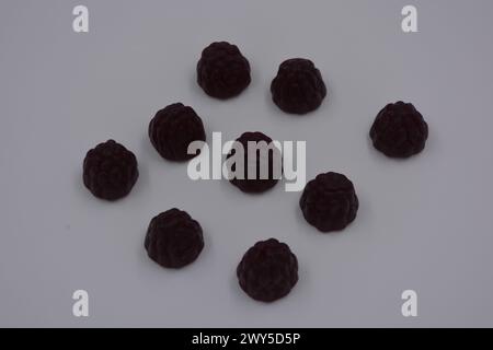 Ungewöhnliche Süßigkeiten, farbige Gelee-Bonbons in Form von Früchten. Schwarze Gelee brombeere und Himbeere sind auf weißem Hintergrund angeordnet. Stockfoto