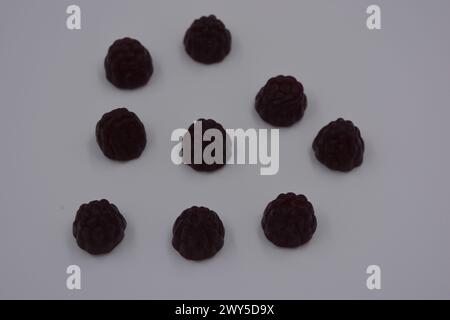 Ungewöhnliche Süßigkeiten, farbige Gelee-Bonbons in Form von Früchten. Schwarze Gelee brombeere und Himbeere sind auf weißem Hintergrund angeordnet. Stockfoto