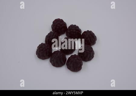 Ungewöhnliche Süßigkeiten, farbige Gelee-Bonbons in Form von Früchten. Schwarze Gelee brombeere und Himbeere sind auf weißem Hintergrund angeordnet. Stockfoto