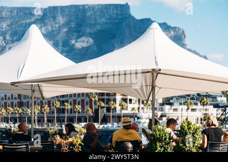 Gäste, die sich in Kapstadts V&A Waterfront mit Blick auf den Tafelberg, Südafrika, entspannen Stockfoto
