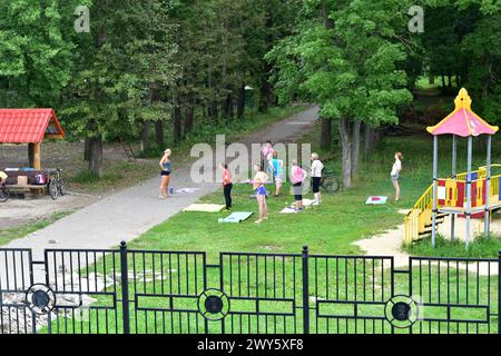 Das Bild zeigt eine Gruppe von Frauen auf einer grünen Wiese im Park, die Morgenübungen macht. Stockfoto