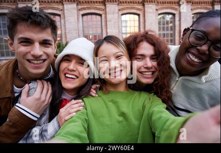 Interrassische Gruppe fröhlicher Freunde, die gemeinsam Selfie im Freien an der Universität machen. Stockfoto